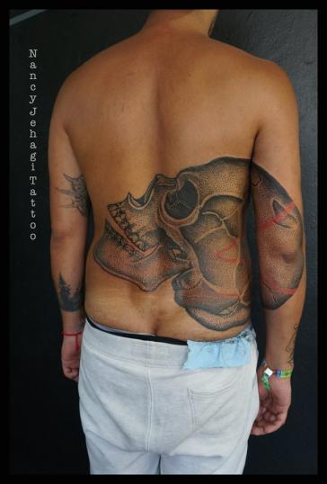 Cráneo espalda y brazo tatuaje realizado por Nancy Jehagi Tattoo