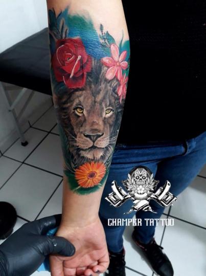 León con flores a color tatuaje realizado por Champer tattoo
