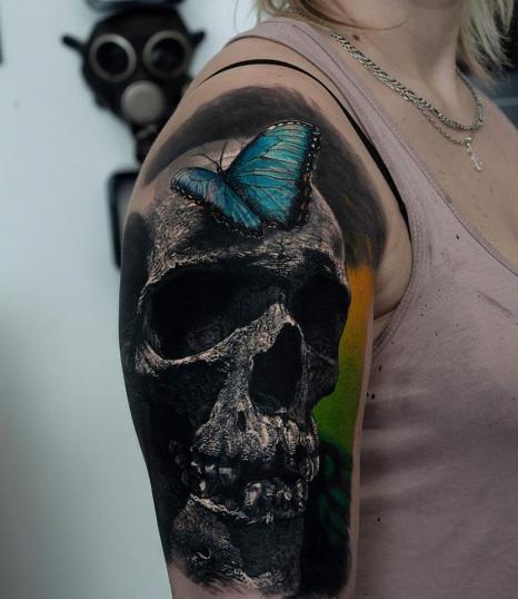 Cráneo y mariposa realismo a color tatuaje realizado por Au Dela du Reel Tattoo