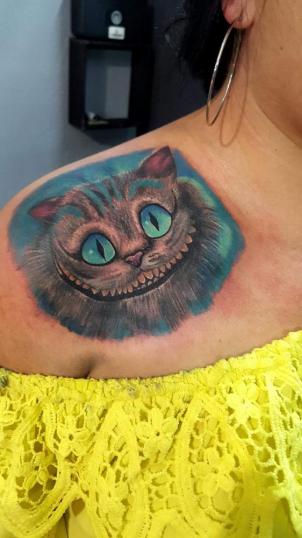 Tatuaje de Cheshire Sonriente realizado por Alejandro Hernández tatuaje realizado por Alejandro Hernández