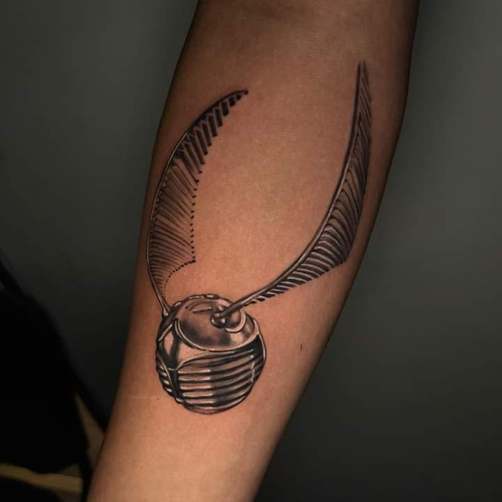 Tatuaje de snitch dorada realizada por Roberto Valencia tatuaje realizado por Roberto Valencia