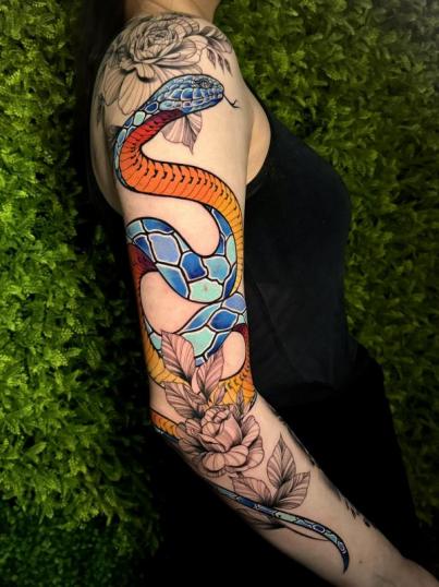 Tatuaje de serpiente y peonias en el brazo realizado por Mani Broowns tatuaje realizado por Mani Broowns