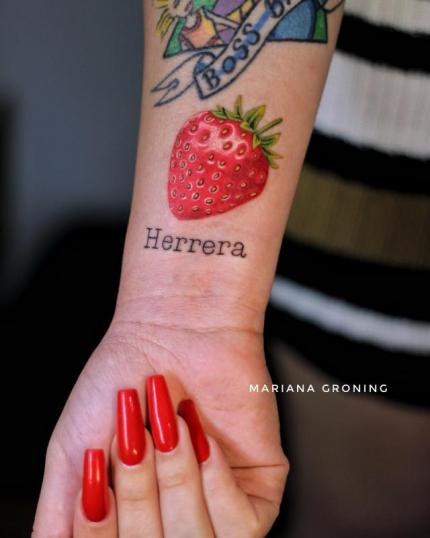 Tatuaje de fresa y apellido Herrera en el antebrazo realizado por Mariana Groning tatuaje realizado por Mariana Groning